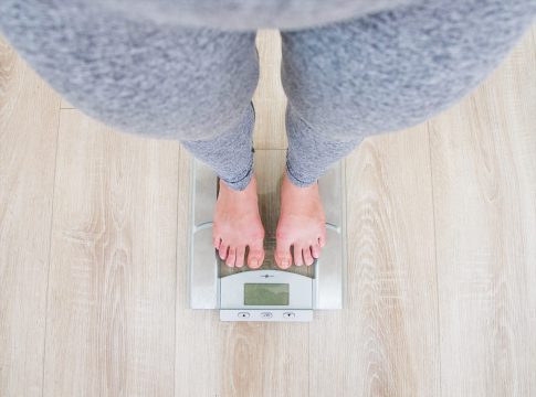 A woman measures her weight on a scale