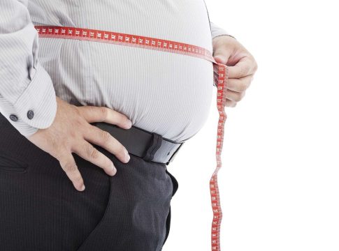 An obese man measures his waist
