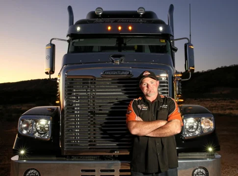 The driver is standing in front of his truck