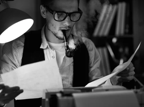 The writer smokes his pipe and reads his work